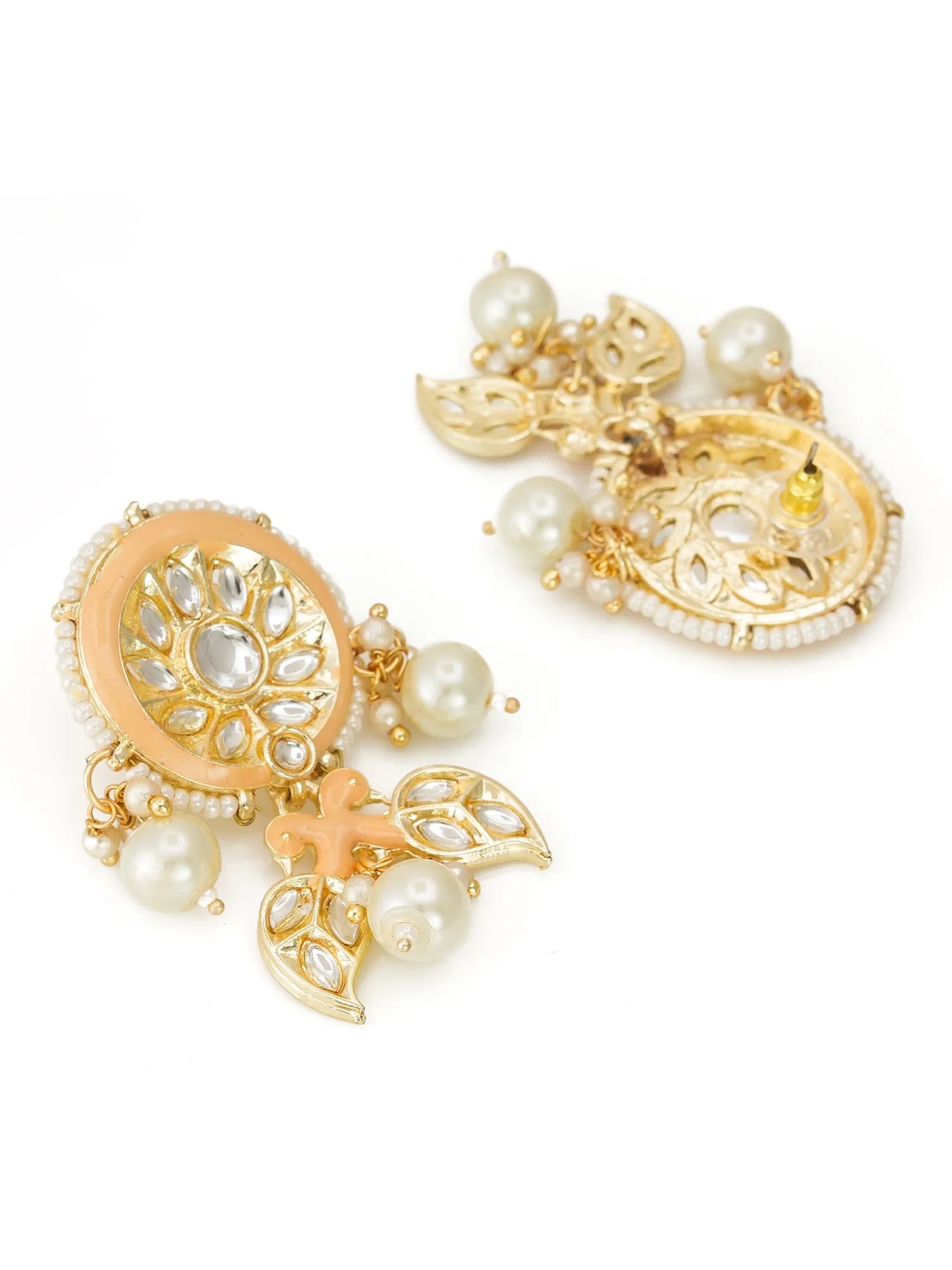 A pair of gold-plated Indian jhumka earrings decorated with white faux pearls, a peach-pink enamel border, and clear stone inlays, displayed on a clean white background.
