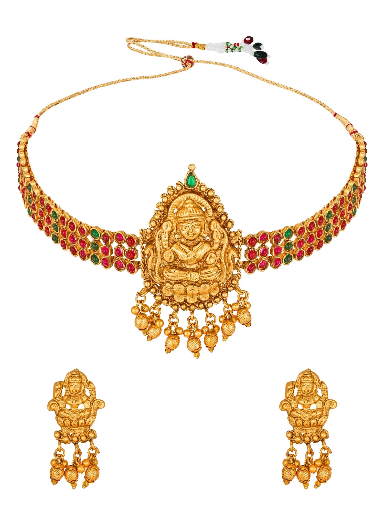 Gold-toned traditional necklace and matching drop earrings featuring a seated deity motif, with red and green stone accents along the curved shoulders and dangling bead chains, shown on a plain white background.