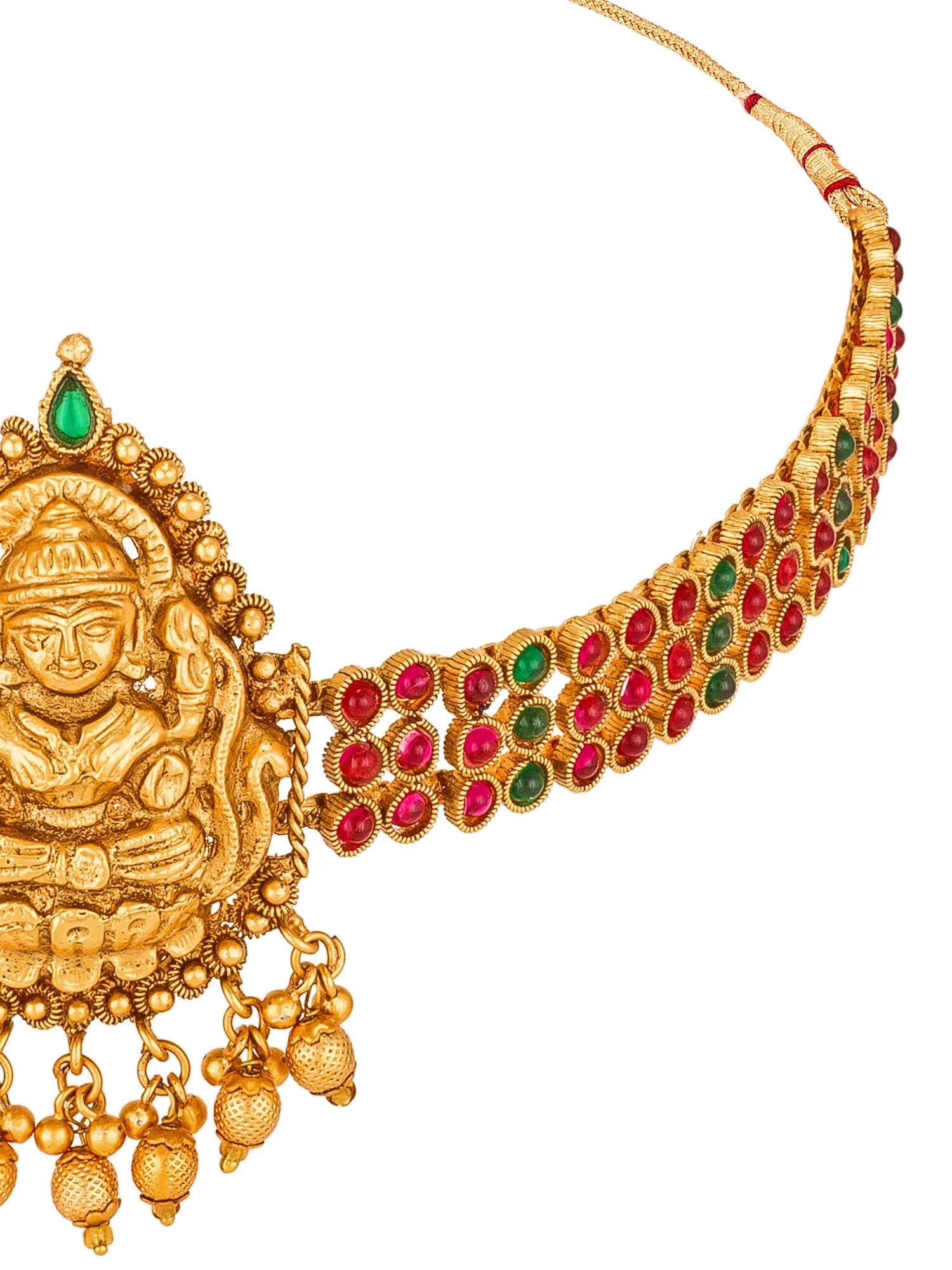 Gold-toned traditional necklace with a deity pendant, red and green gemstone accents, and dangling bead charms on a white background.