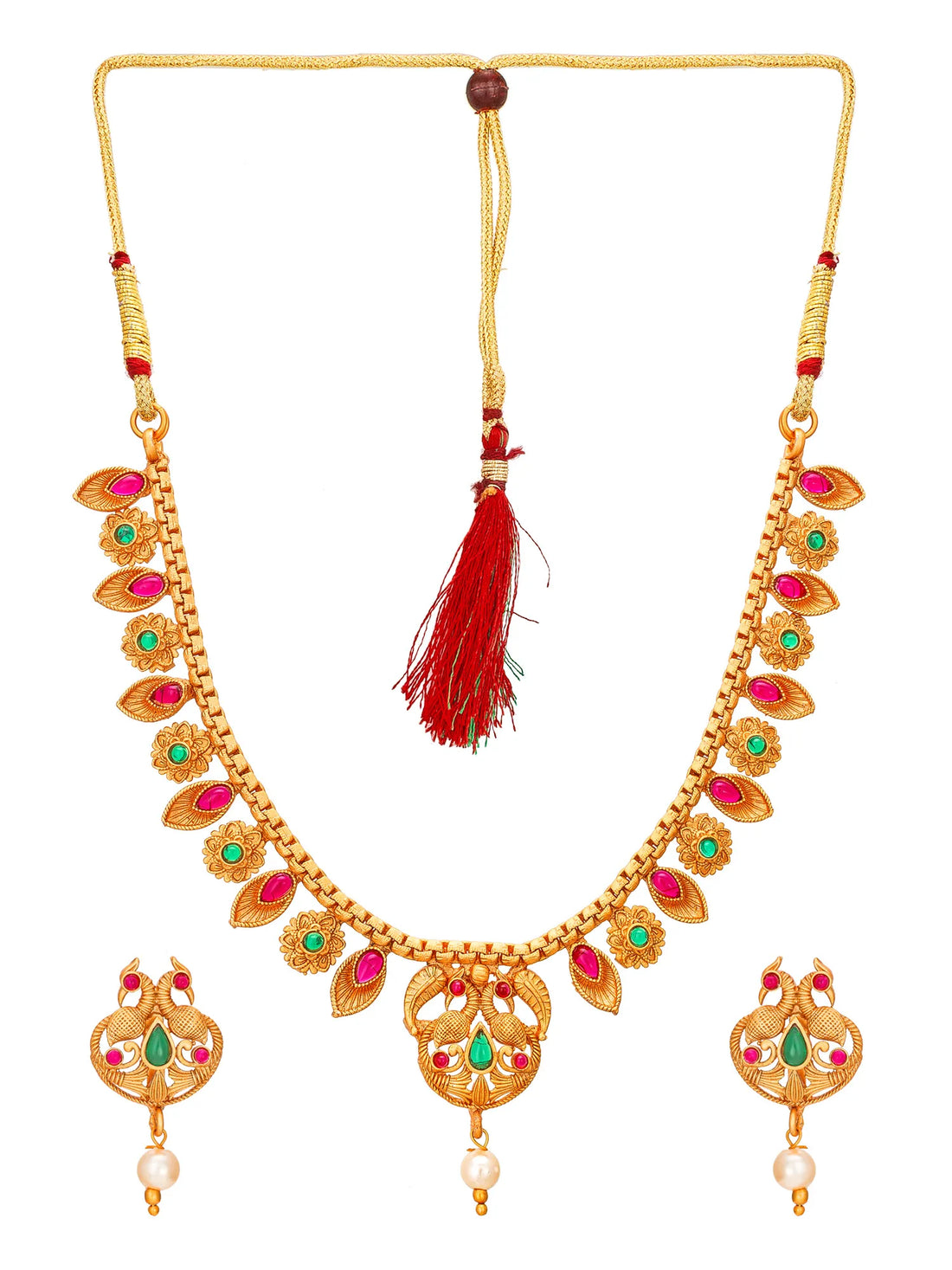 Gold-toned traditional Indian jewelry set featuring a necklace and matching earrings with red and green stone accents and pearl details, displayed on a dark background with red fabric.