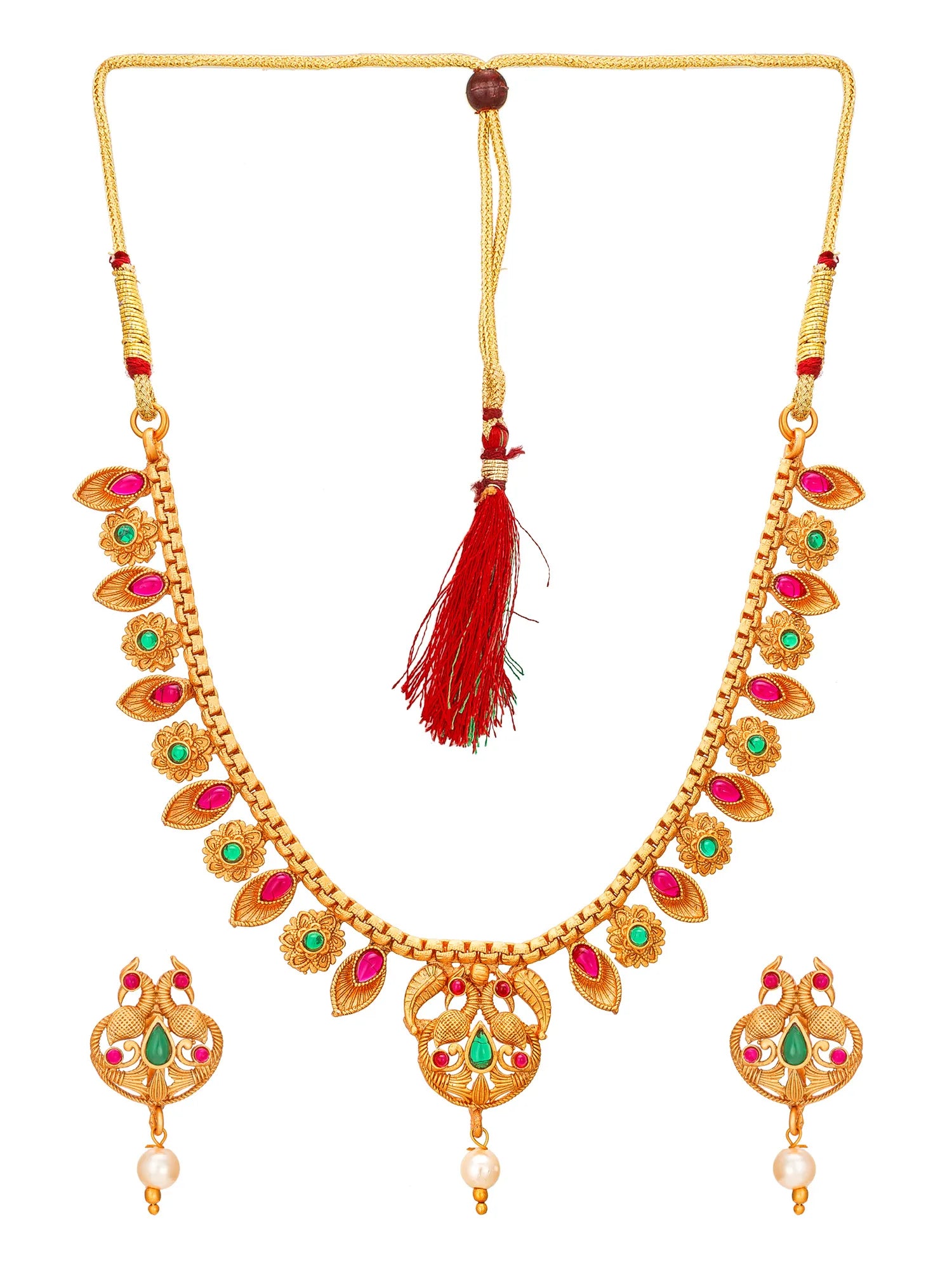 Gold-plated Indian jewelry set featuring a necklace with red and green stone accents, a red tassel, and matching dangle earrings with pearl drops, shown on a white background.