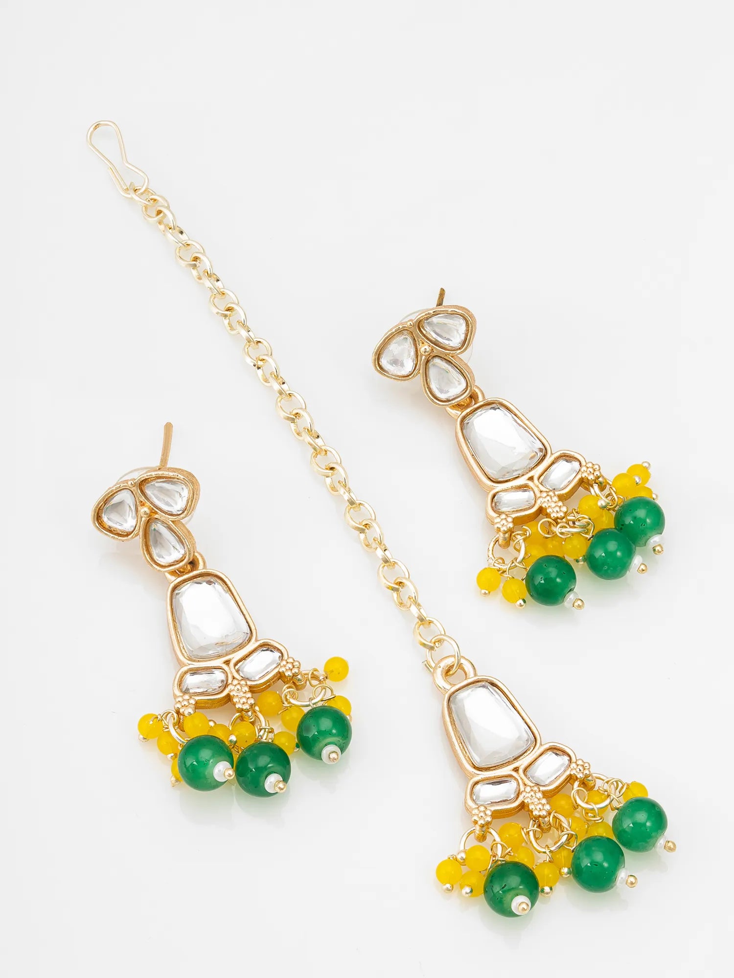 Gold-toned traditional Indian jhumka earrings with white teardrop inlays, green bead drops, and yellow bead accents, displayed on a clean white background.