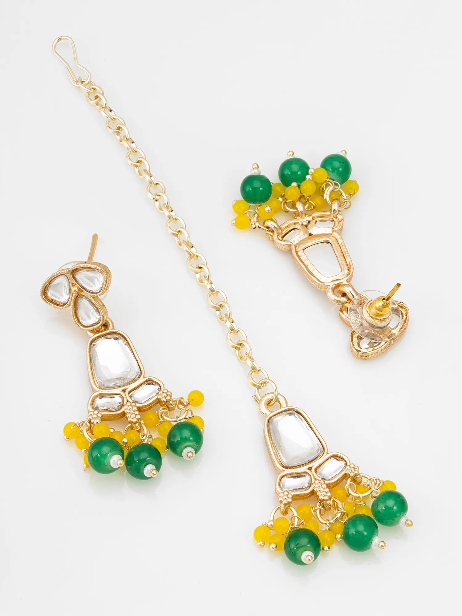 Gold-toned Indian jhumka earrings with green and yellow beads, white stone accents, and a matching chain, displayed on a clean white background.