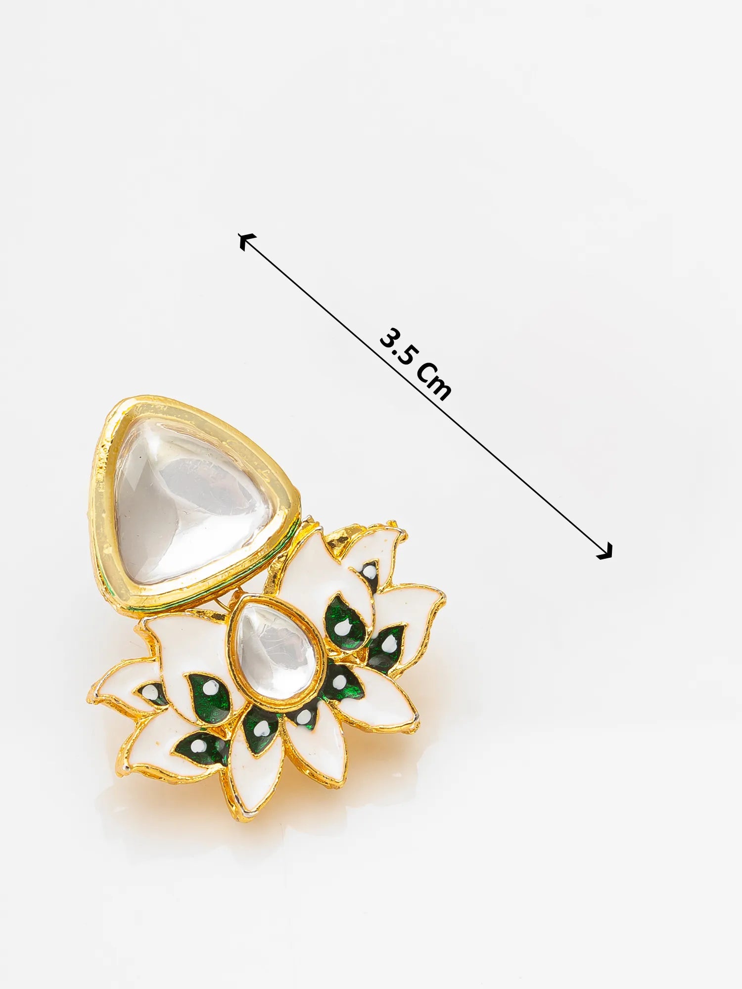 A gold-toned South Indian style kumkum box pendant with a lotus flower and teardrop motif, decorated with white enamel, green stones, and clear crystals. A black dimension line with '3.