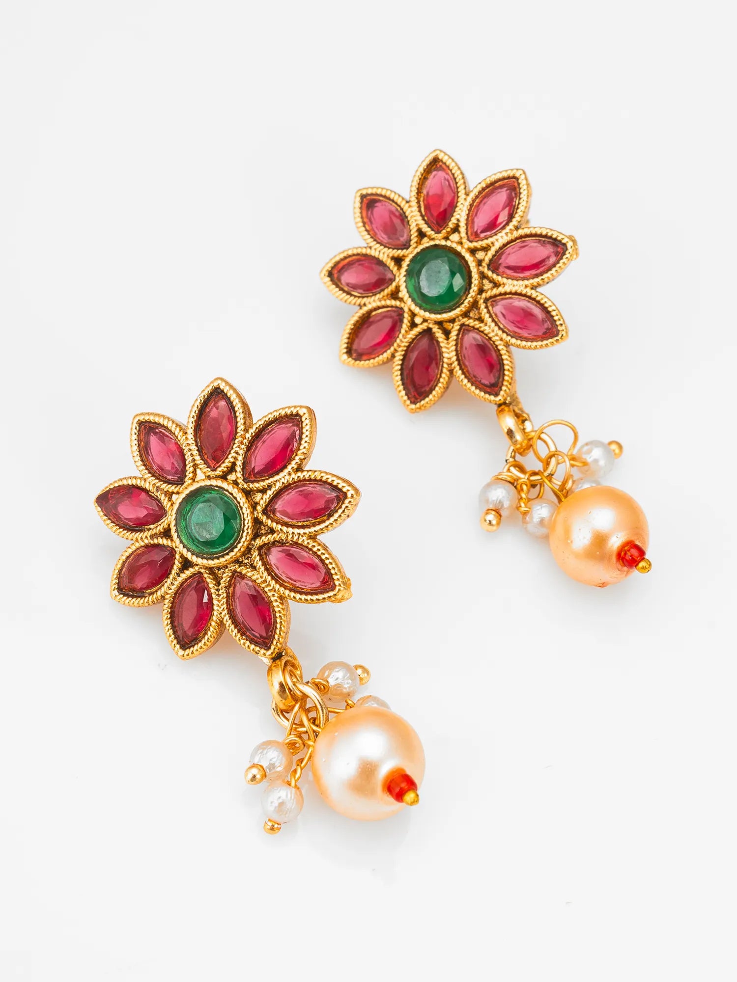 A pair of gold-plated floral dangle earrings featuring pink marquise-cut stones, a central green oval stone, and dangling peach pearls with small white pearl accents, set against a plain white background.