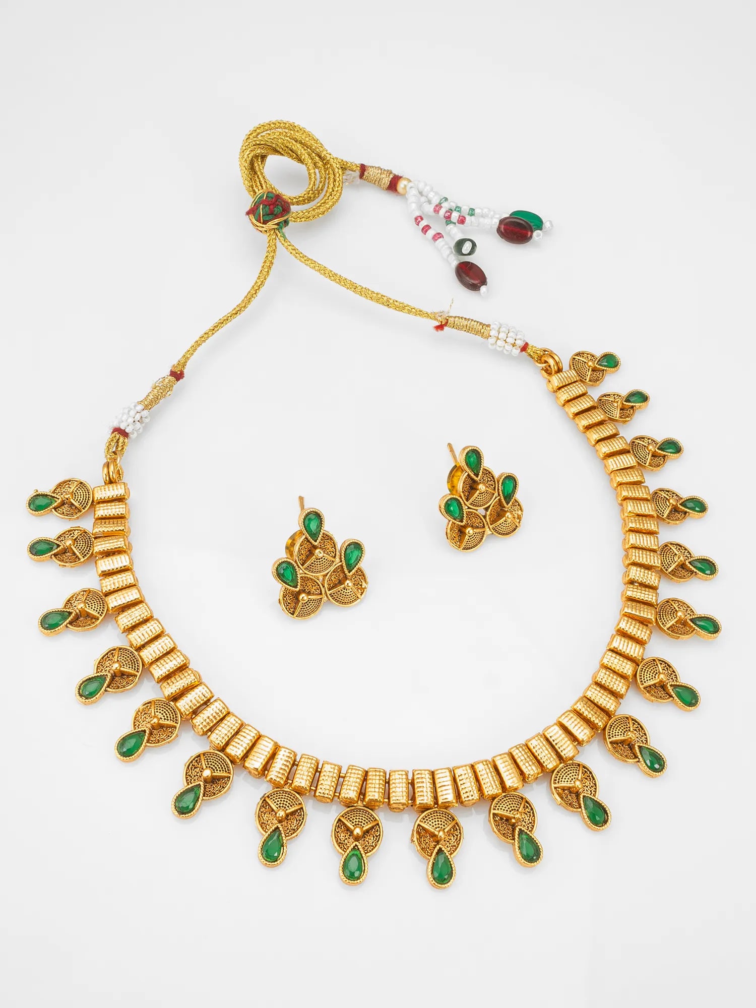 Gold-plated traditional Indian jewelry set featuring a necklace, matching earrings, and a beaded tassel, decorated with green stone accents on a white background.