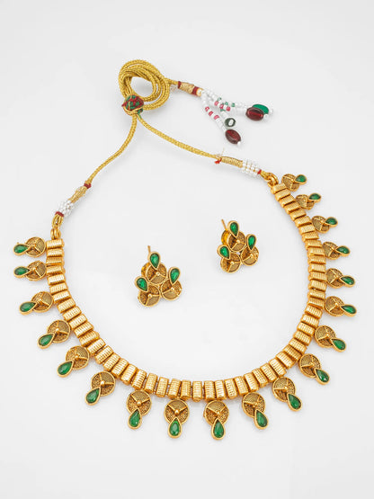 Gold-plated traditional Indian jewelry set featuring a necklace, matching earrings, and a beaded tassel, decorated with green stone accents on a white background.