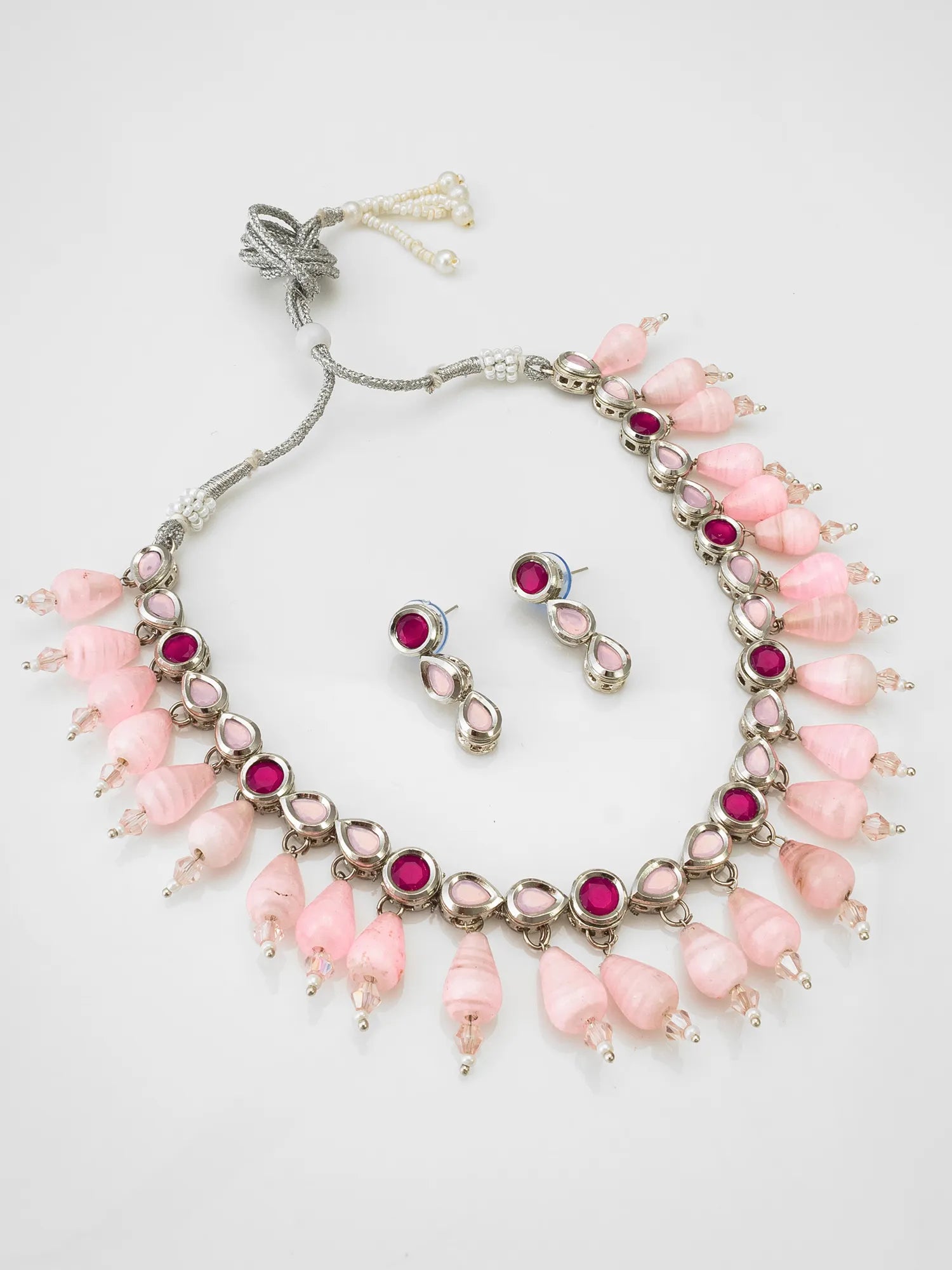 Necklace and earrings set with pink beads and red gemstones on a white background