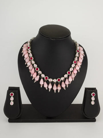 Pink beaded statement necklace with matching drop earrings, displayed on a black jewelry bust against a light gray background.