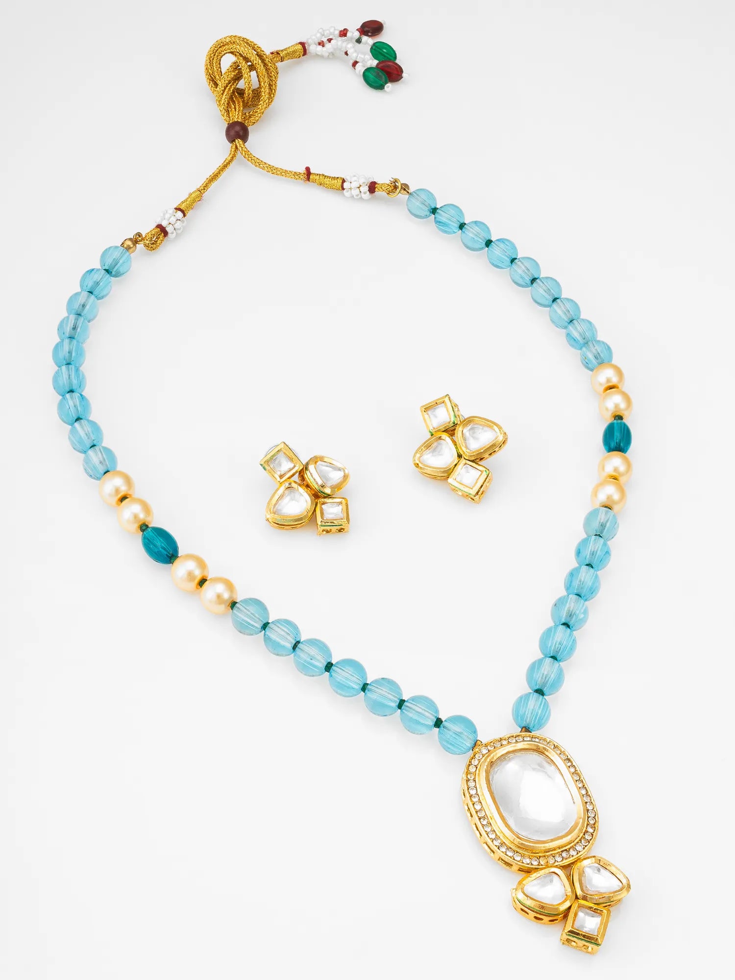 Gold-plated beaded necklace and matching stud earrings set. The necklace features light blue faceted beads, small gold pearls, and a large oval white stone pendant with gold detailing, accompanied by two matching stud earrings.