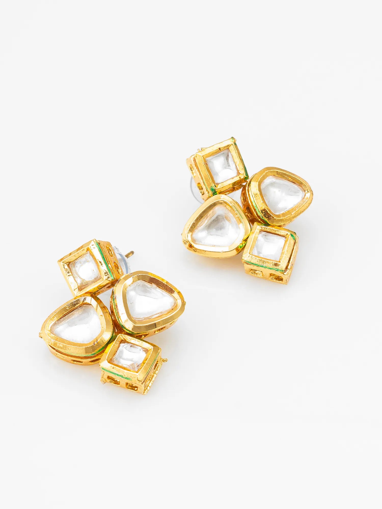 A pair of gold-plated kumkum earrings featuring clear teardrop-shaped and square-shaped stones, accented with small green enamel details, set against a plain white background.