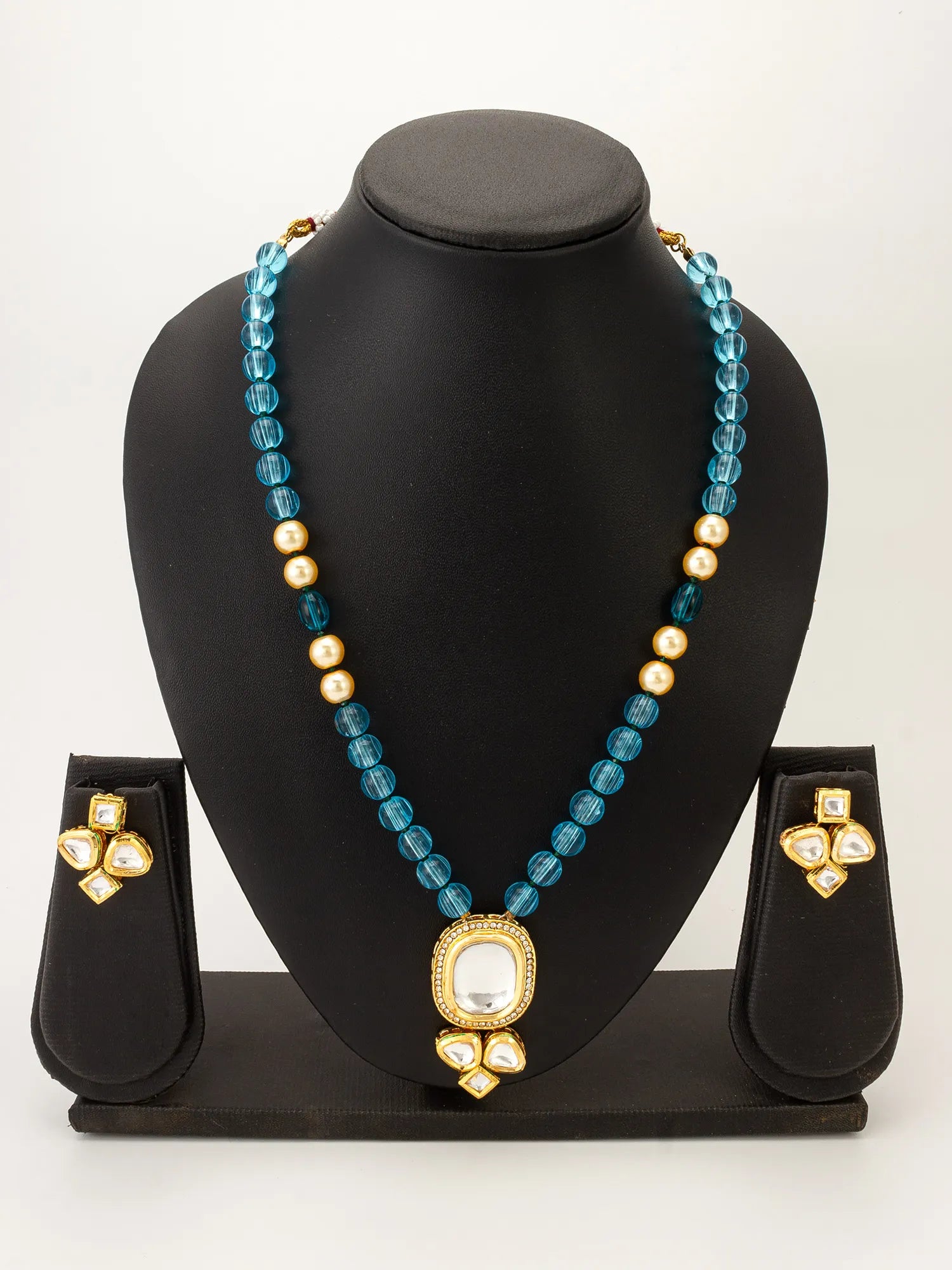 A gold and turquoise blue beaded necklace with a matching pair of stud earrings, displayed on a black jewelry bust against a white background.