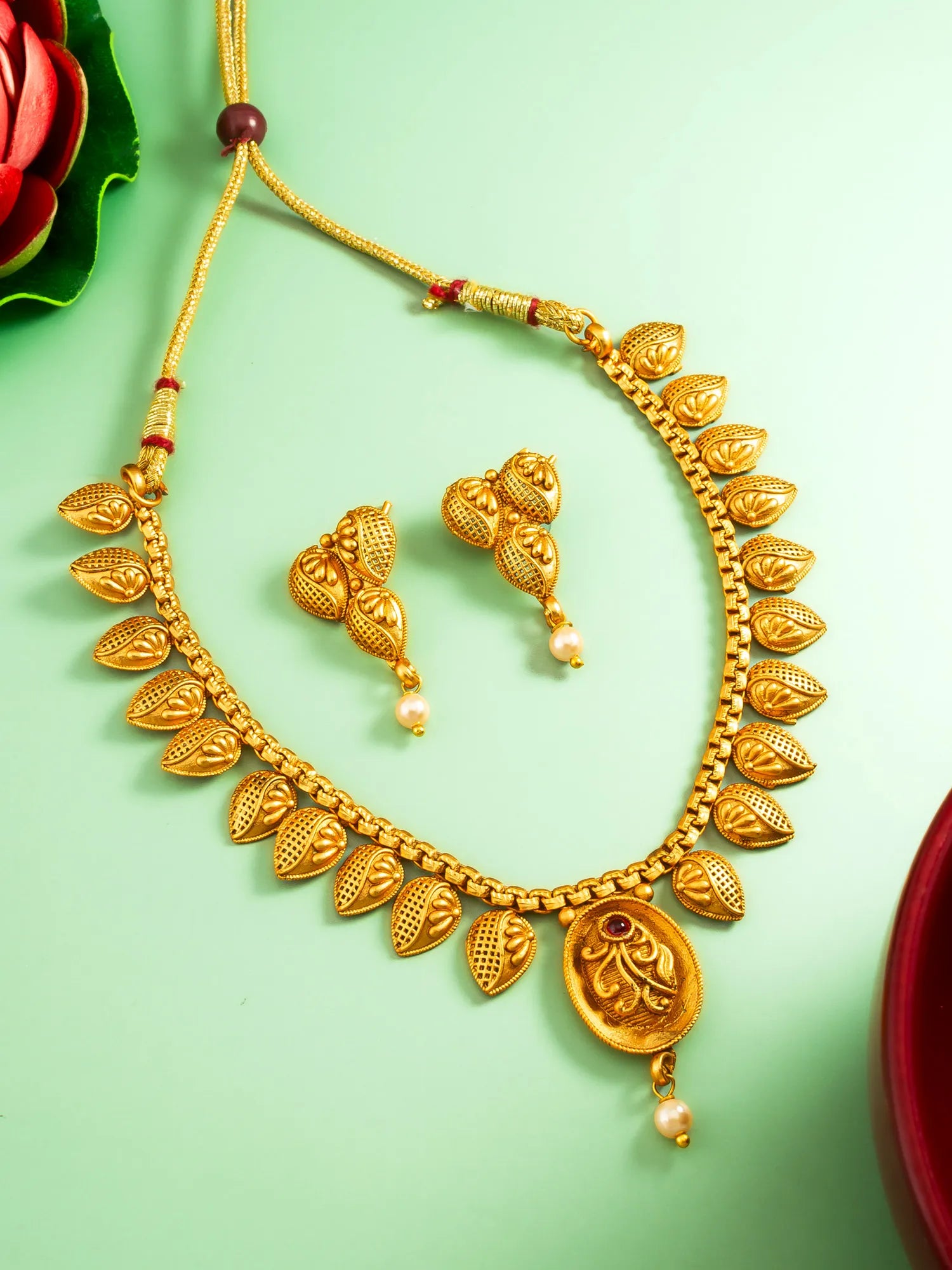 Gold necklace and earrings on a green background