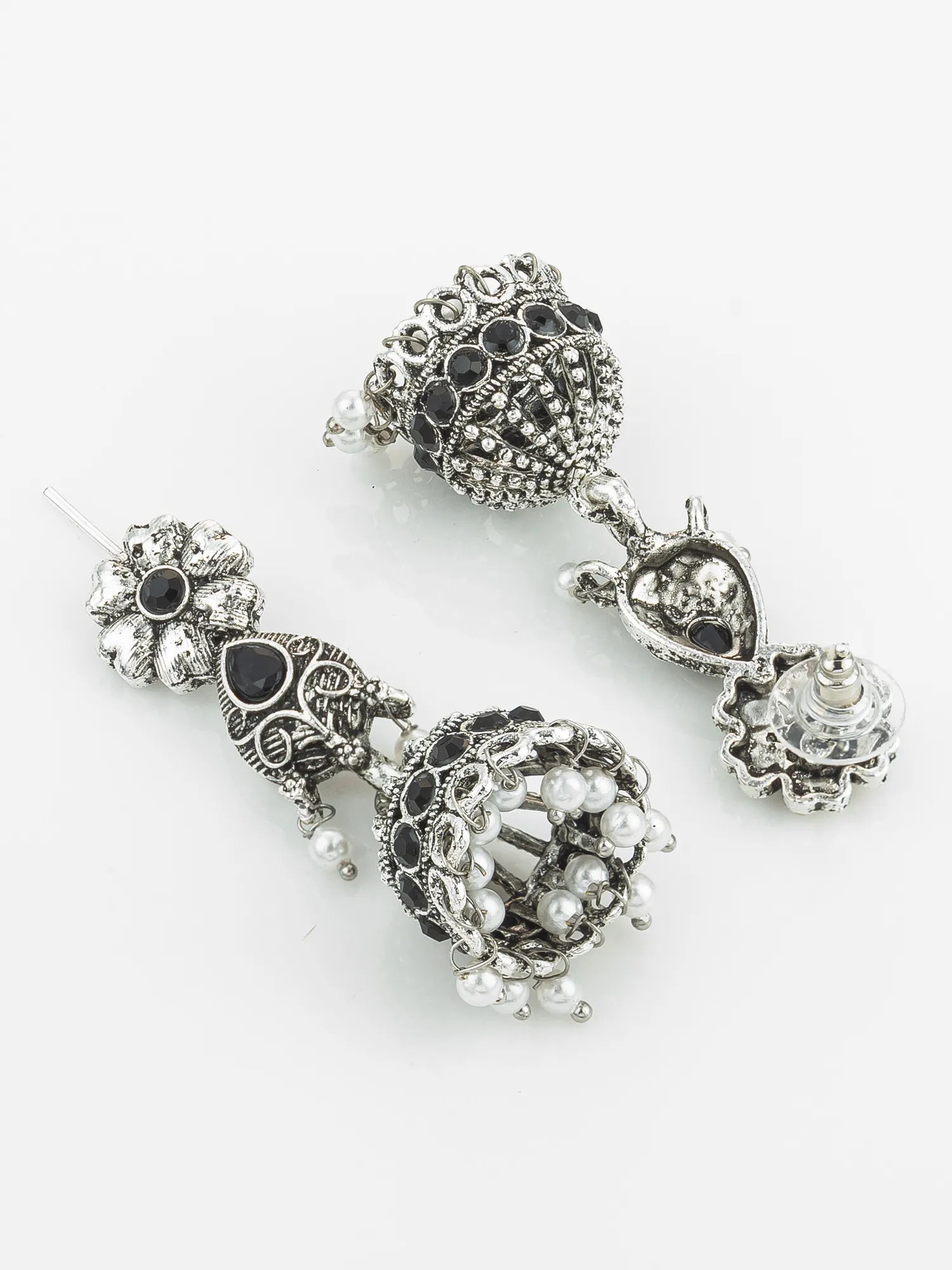 Pair of ornate silver earrings with black and clear gemstones on a white background