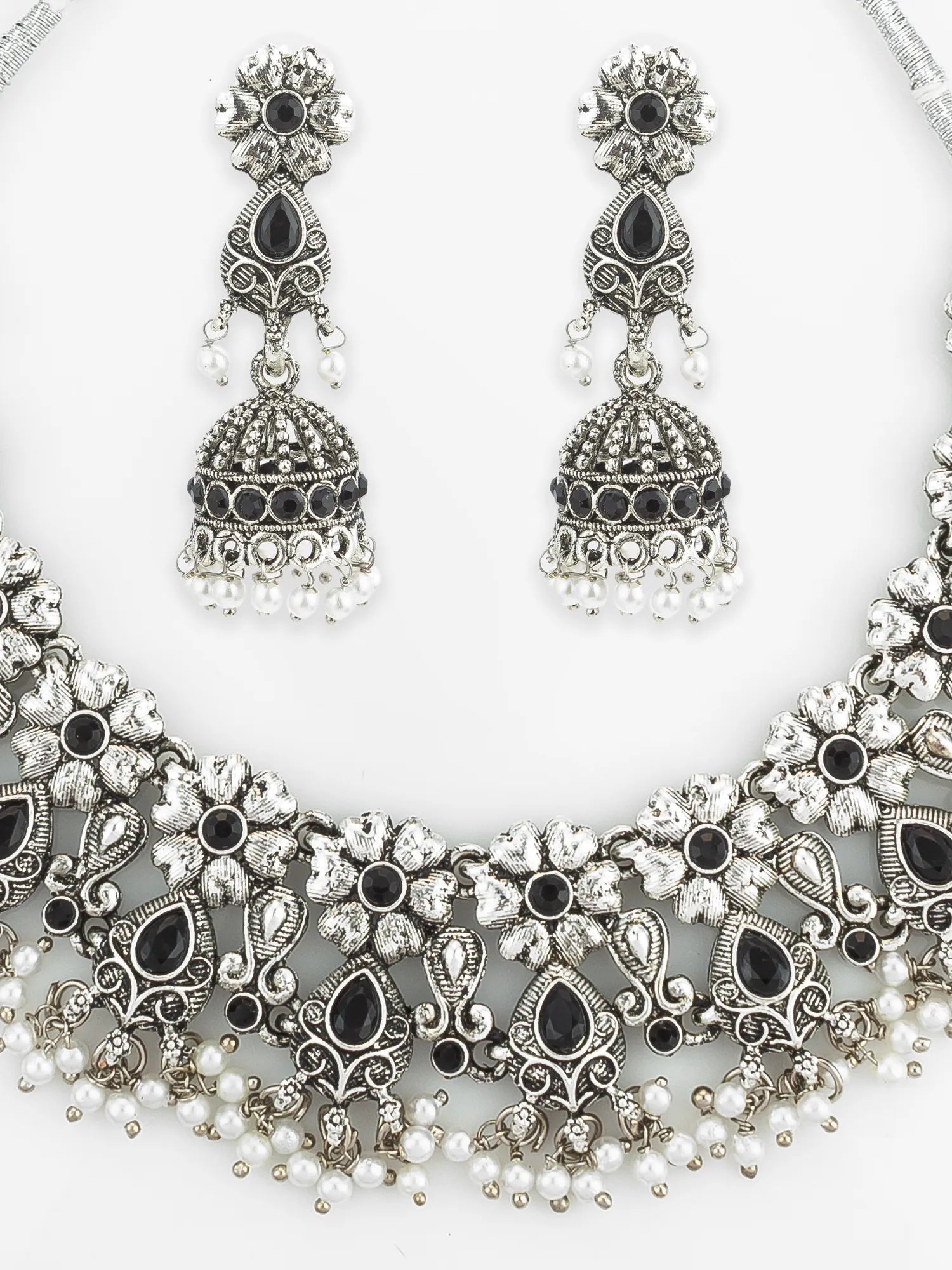 Ornate silver necklace with black and white stones and matching earrings on a white background