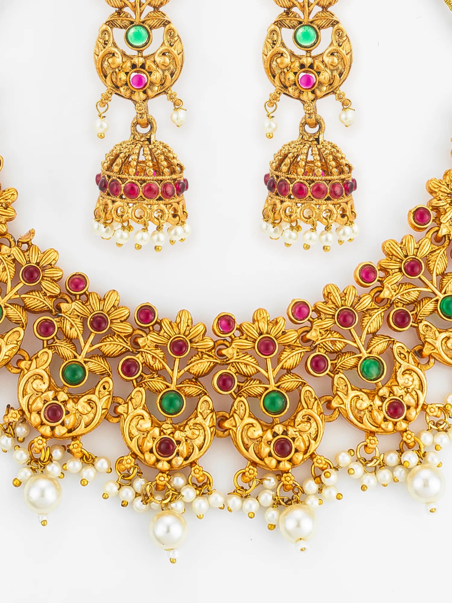 Gold necklace with red and green gemstones and pearl drops on a white background