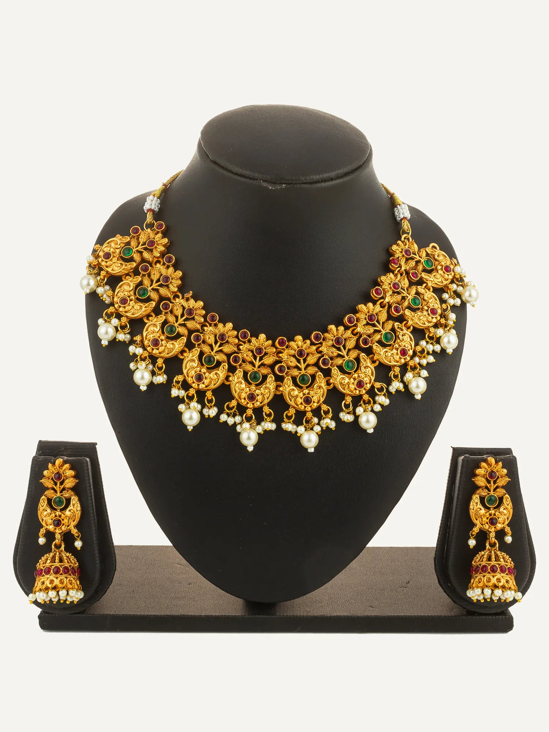 Gold necklace and earrings with gemstones on a green surface