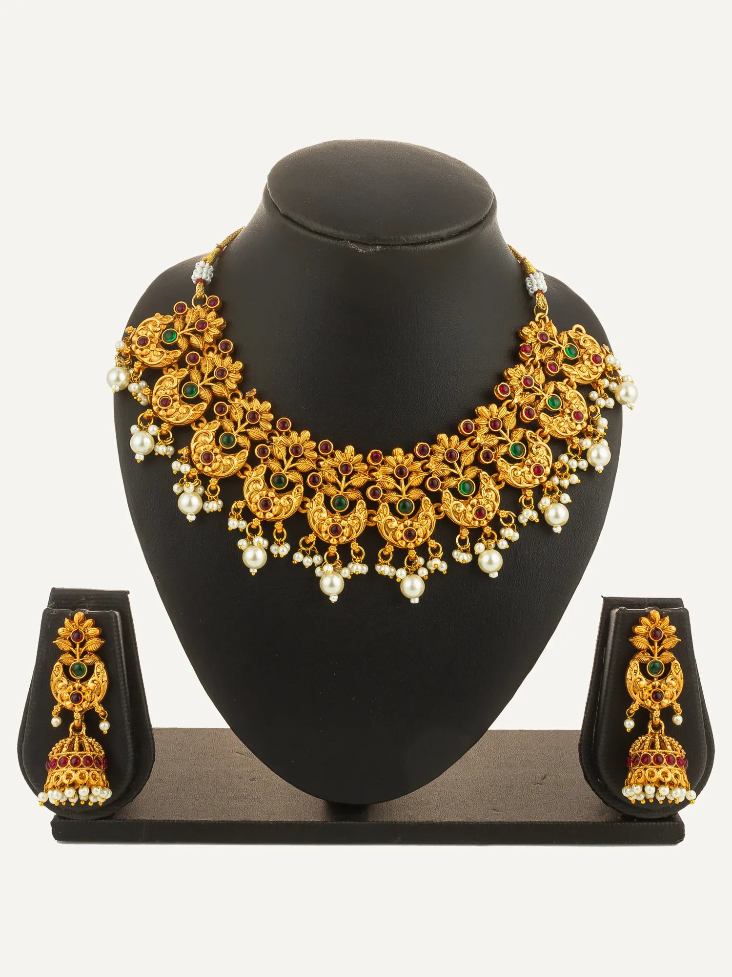 Gold necklace with green and red stones on a black mannequin bust with matching earrings.