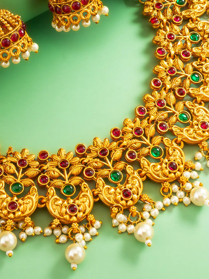 Gold necklace with red and green gemstones and pearls on a green background