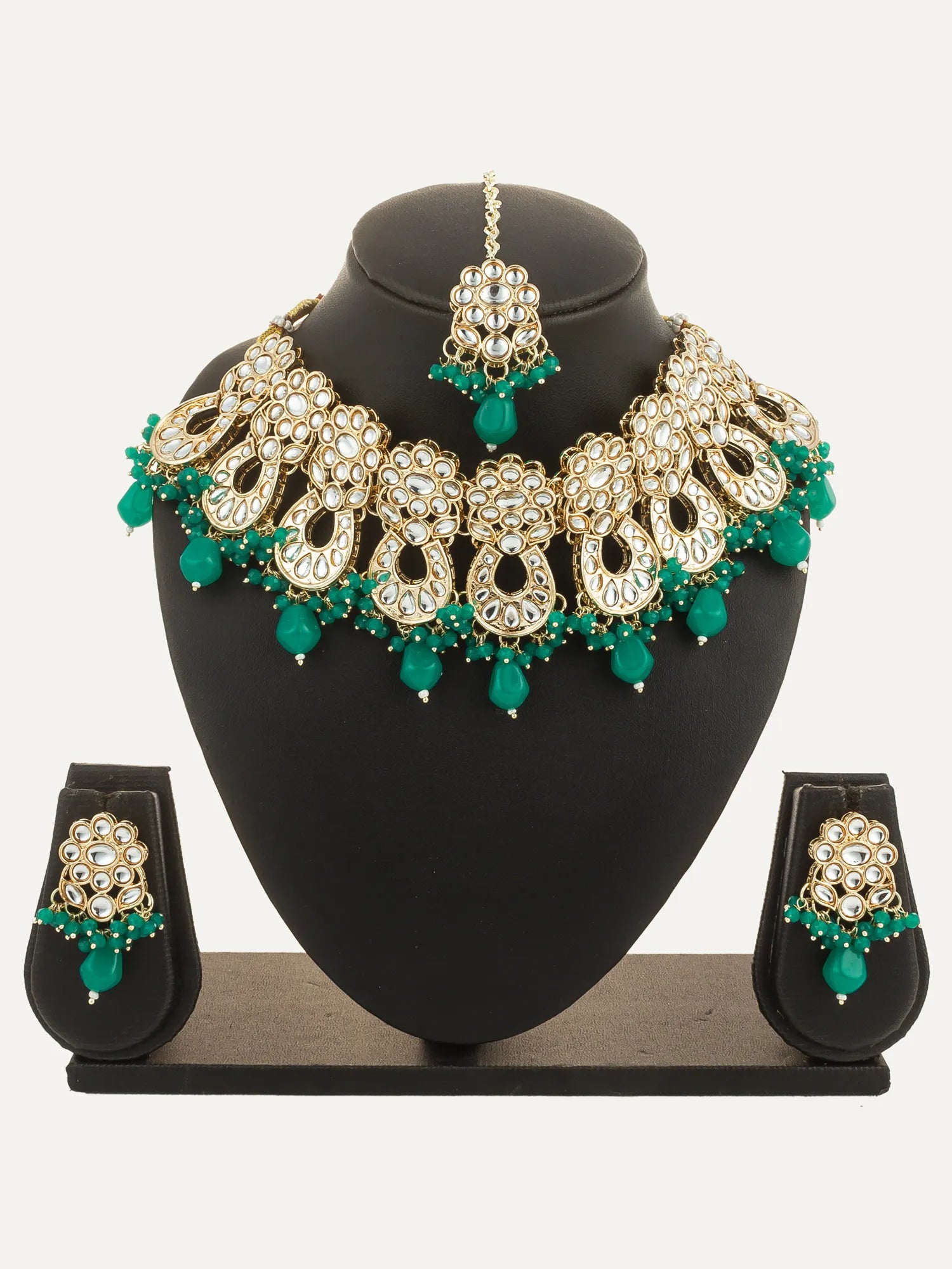 Jewelry set with necklace, earrings, and tikka on a black stand against a white background