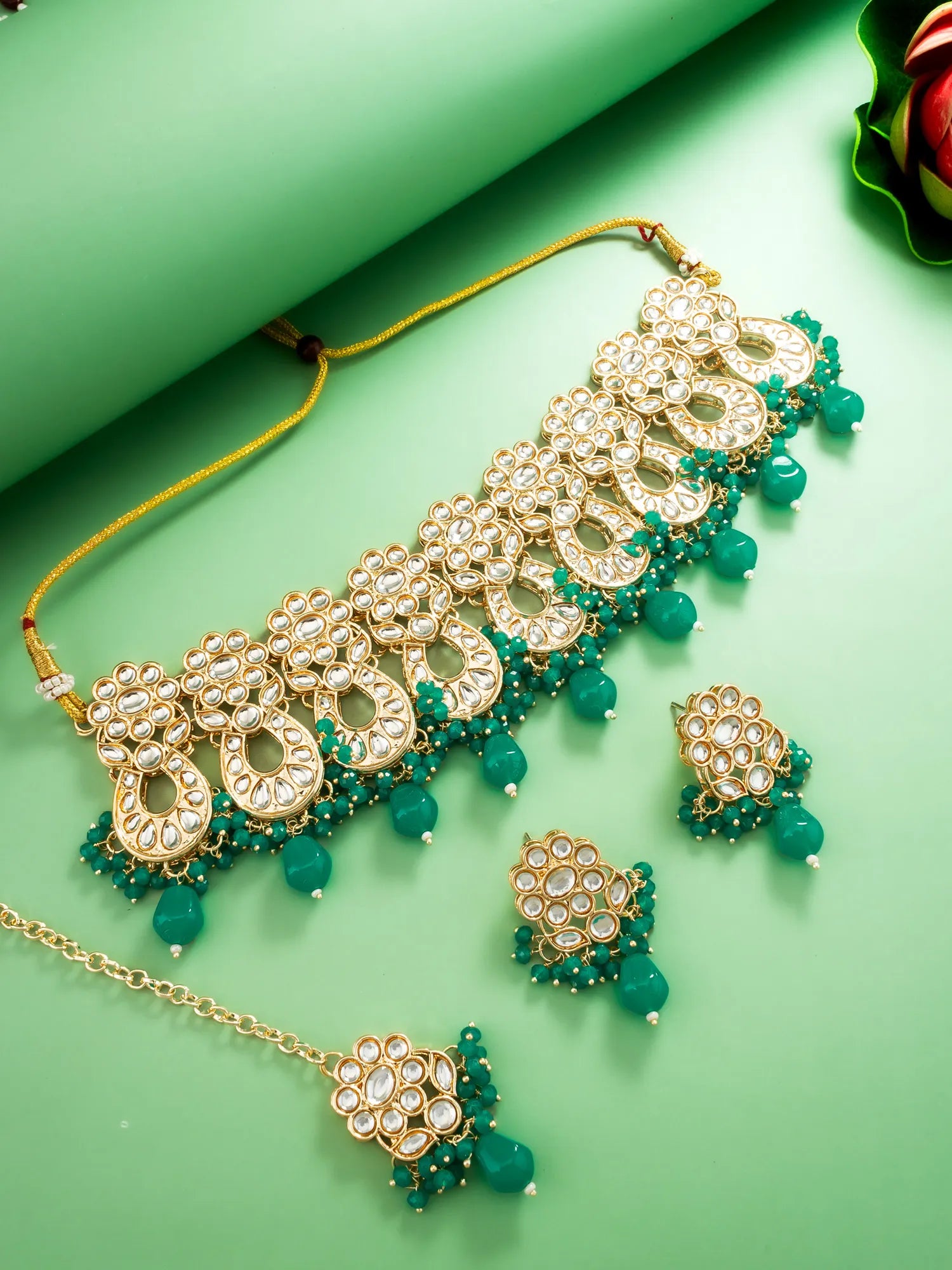 Gold and green jewelry set on a green background
