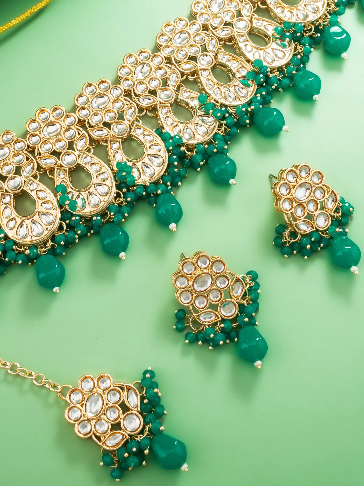 Ornate gold and green jewelry set on a green background
