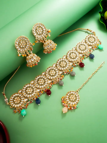 Ornate gold jewelry set with colorful beads on a green background