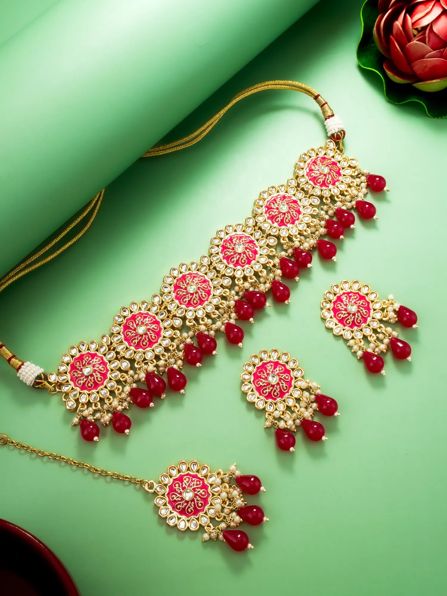 Decorative gold necklace with red stones on a green background