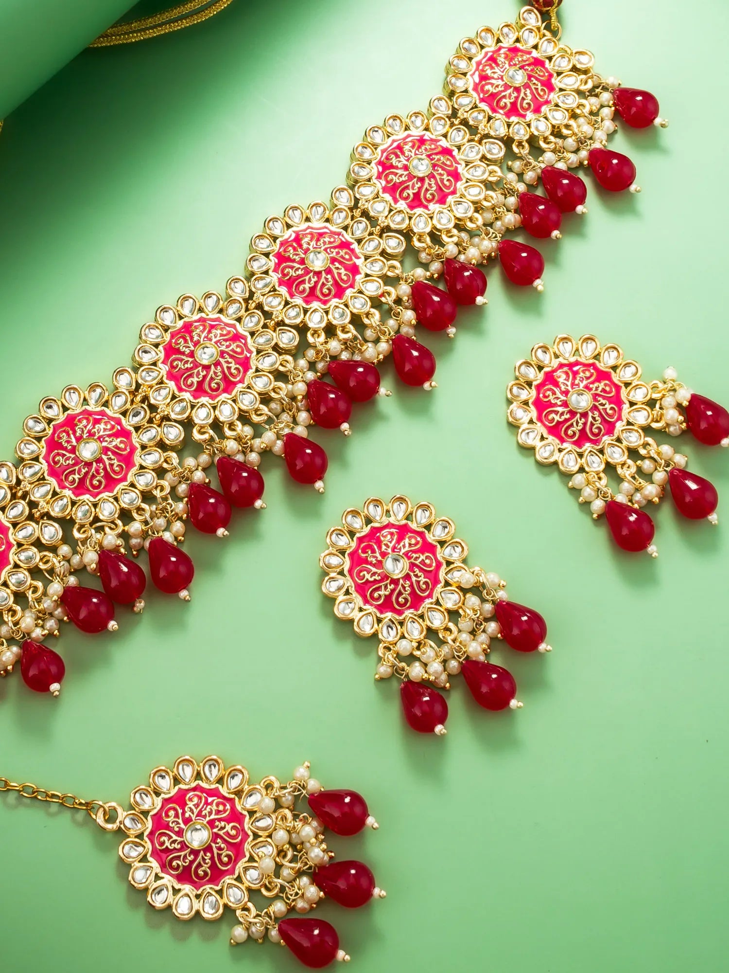 Ornate jewelry set with red stones on a green background