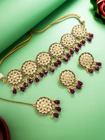 Ornate gold necklace with purple stones on a green background