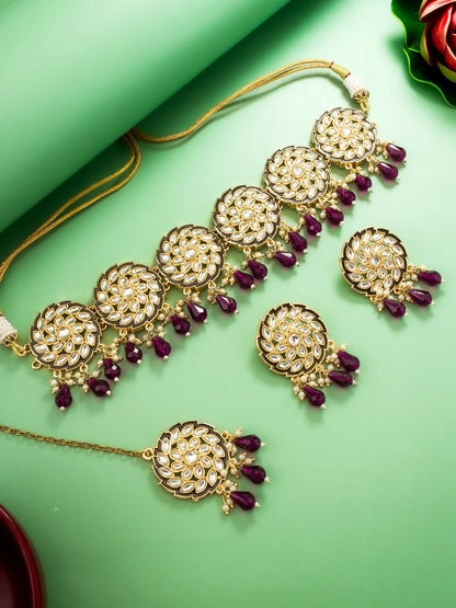 Ornate gold necklace with purple stones on a green background
