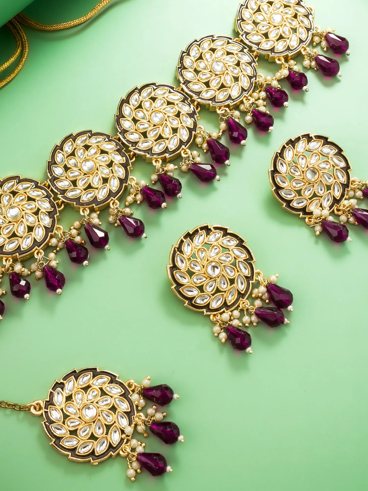Gold and purple jewelry set on a green background