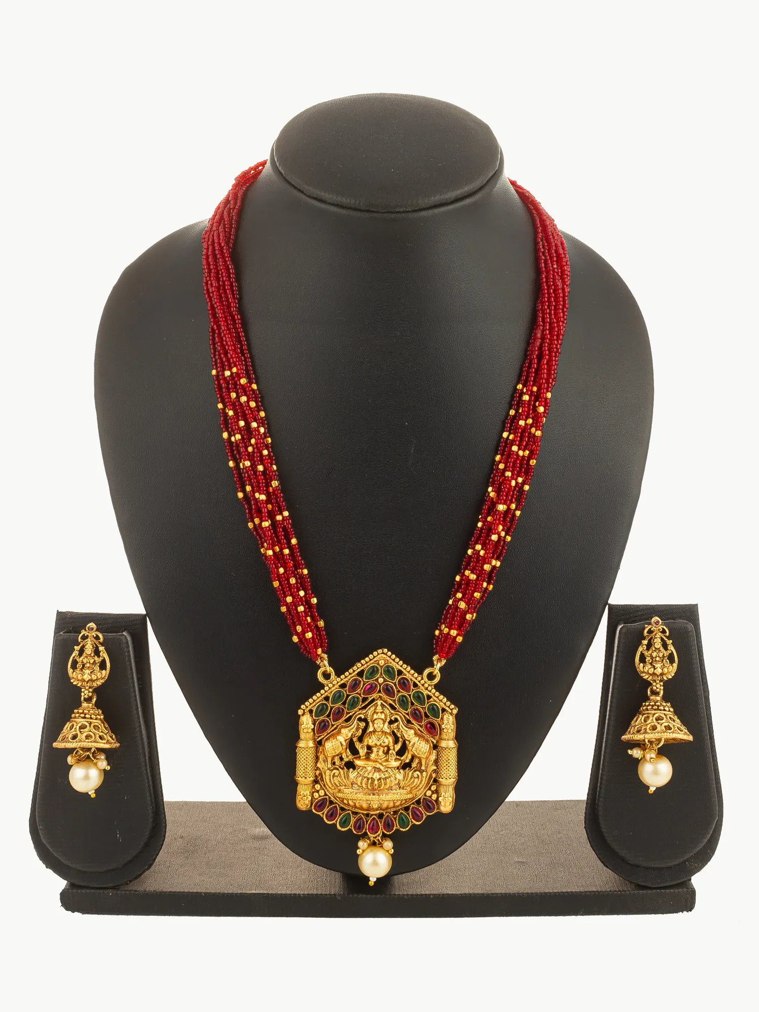 Gold necklace with red beads and matching earrings on a black stand