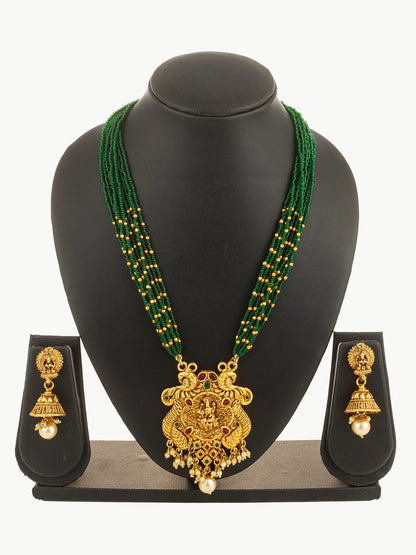 Gold necklace with green beads and matching earrings on a black stand