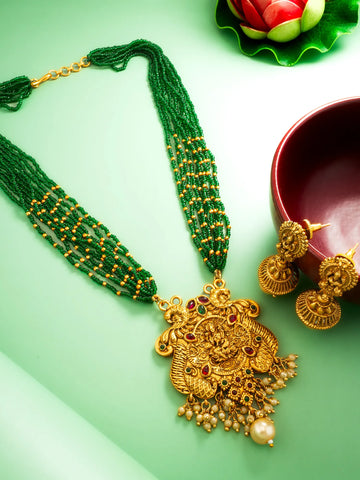 Gold necklace with green beads and matching earrings on a green background