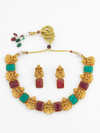 Gold necklace with red and green stones on a white background