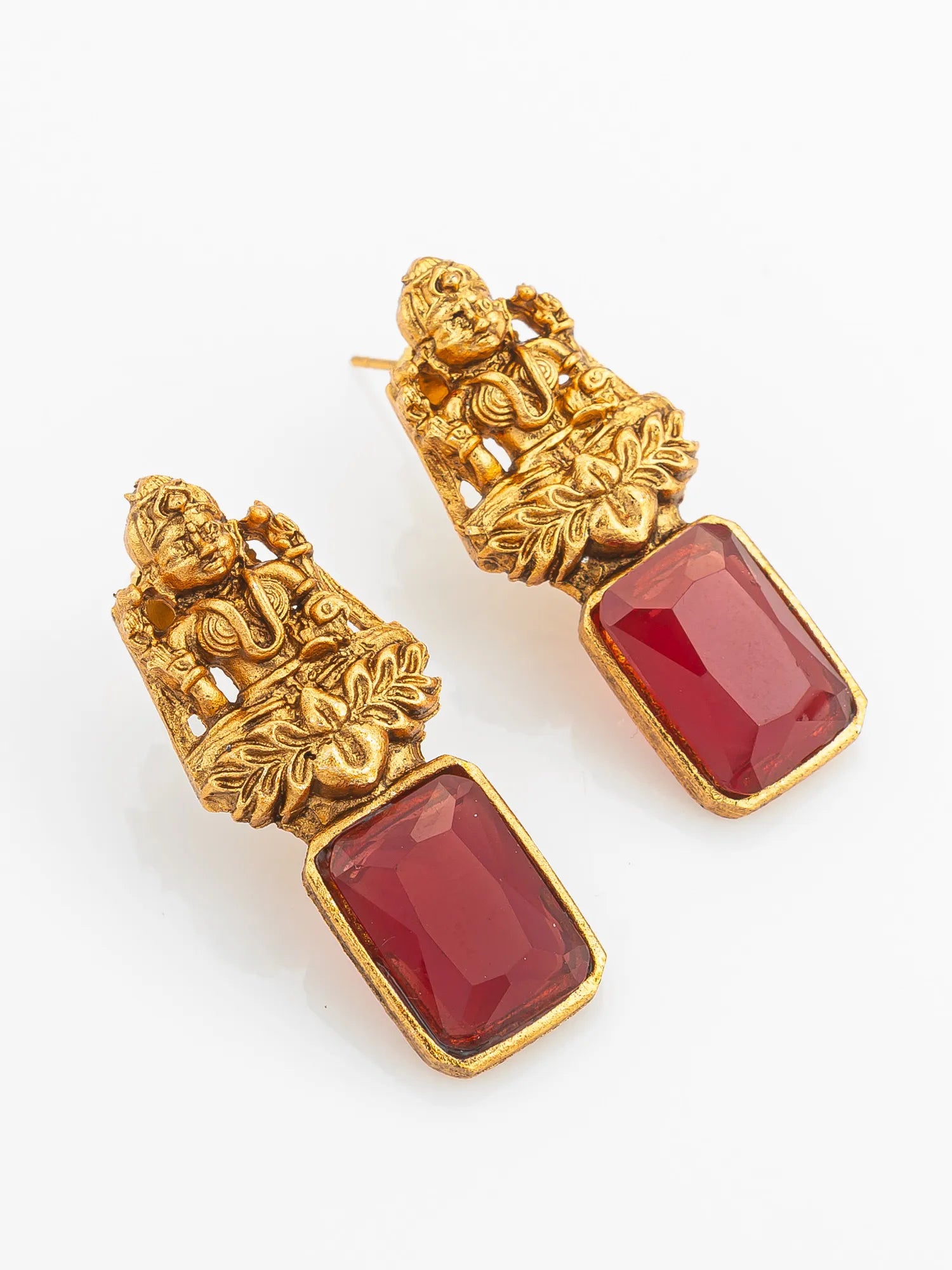 Gold earrings with red gemstones on a white background