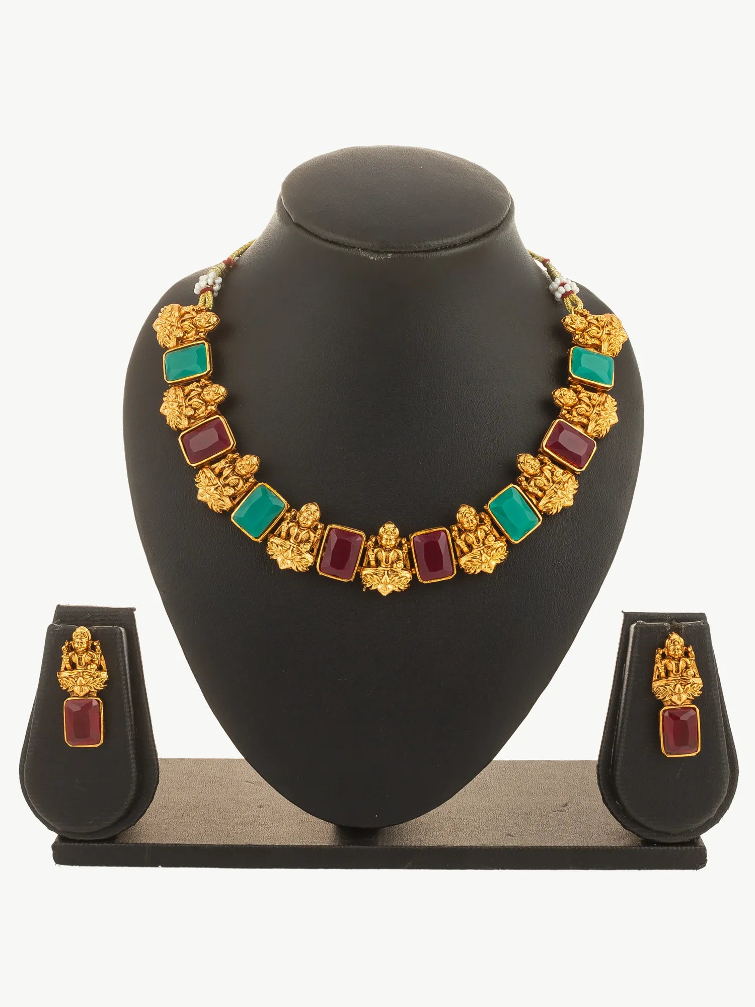Gold necklace with colorful stones and matching earrings on a black mannequin.