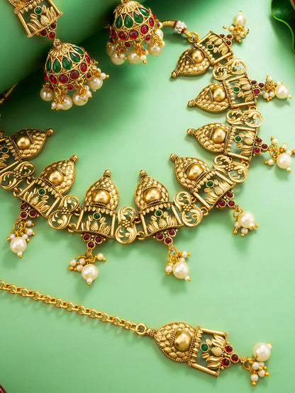 Gold necklace with pearls and gemstones on a green background