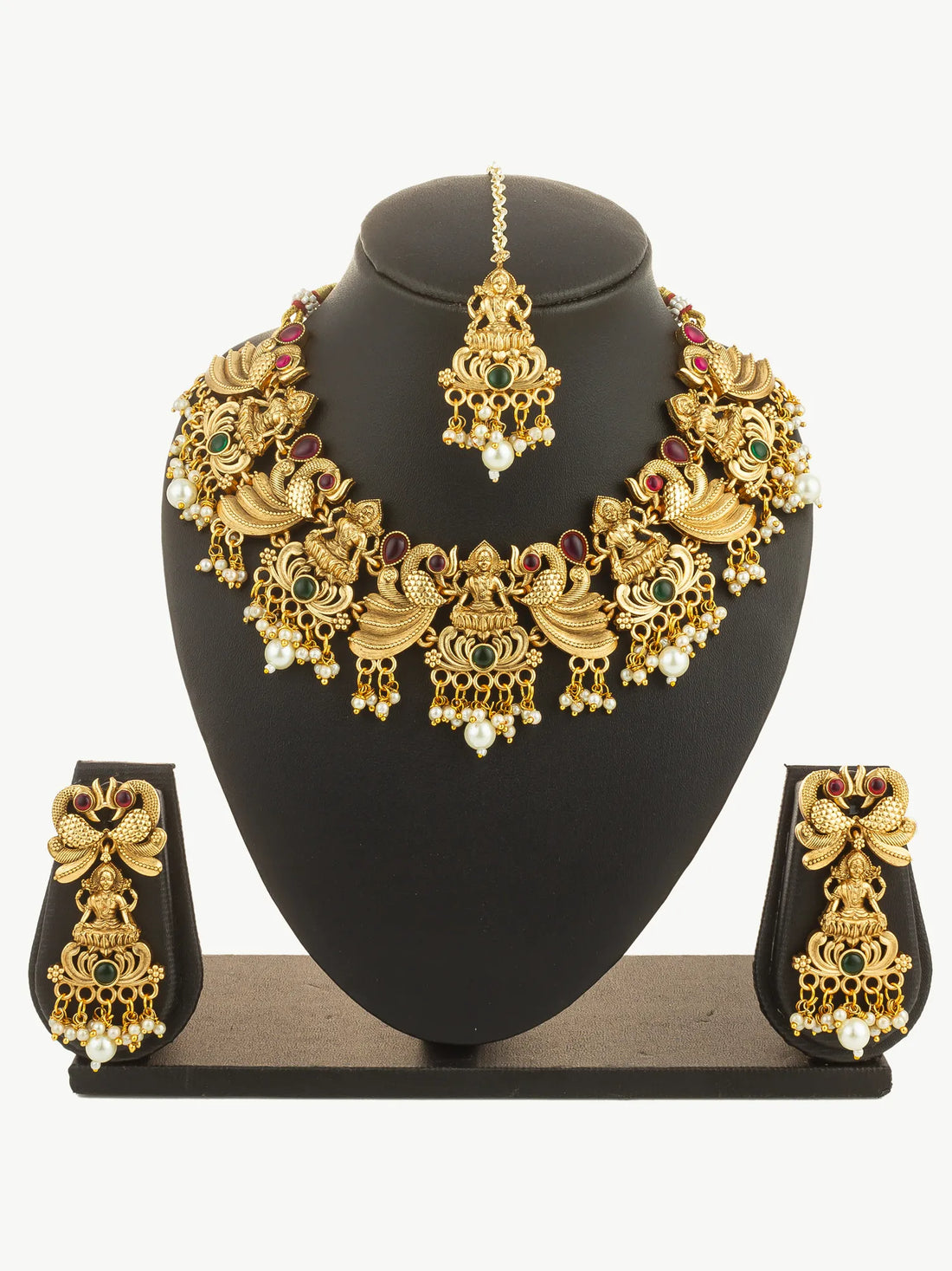 Gold necklace with red and green stones on a green background