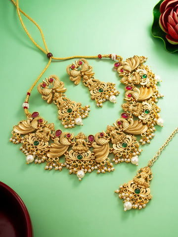 Gold necklace with red and green stones on a green background