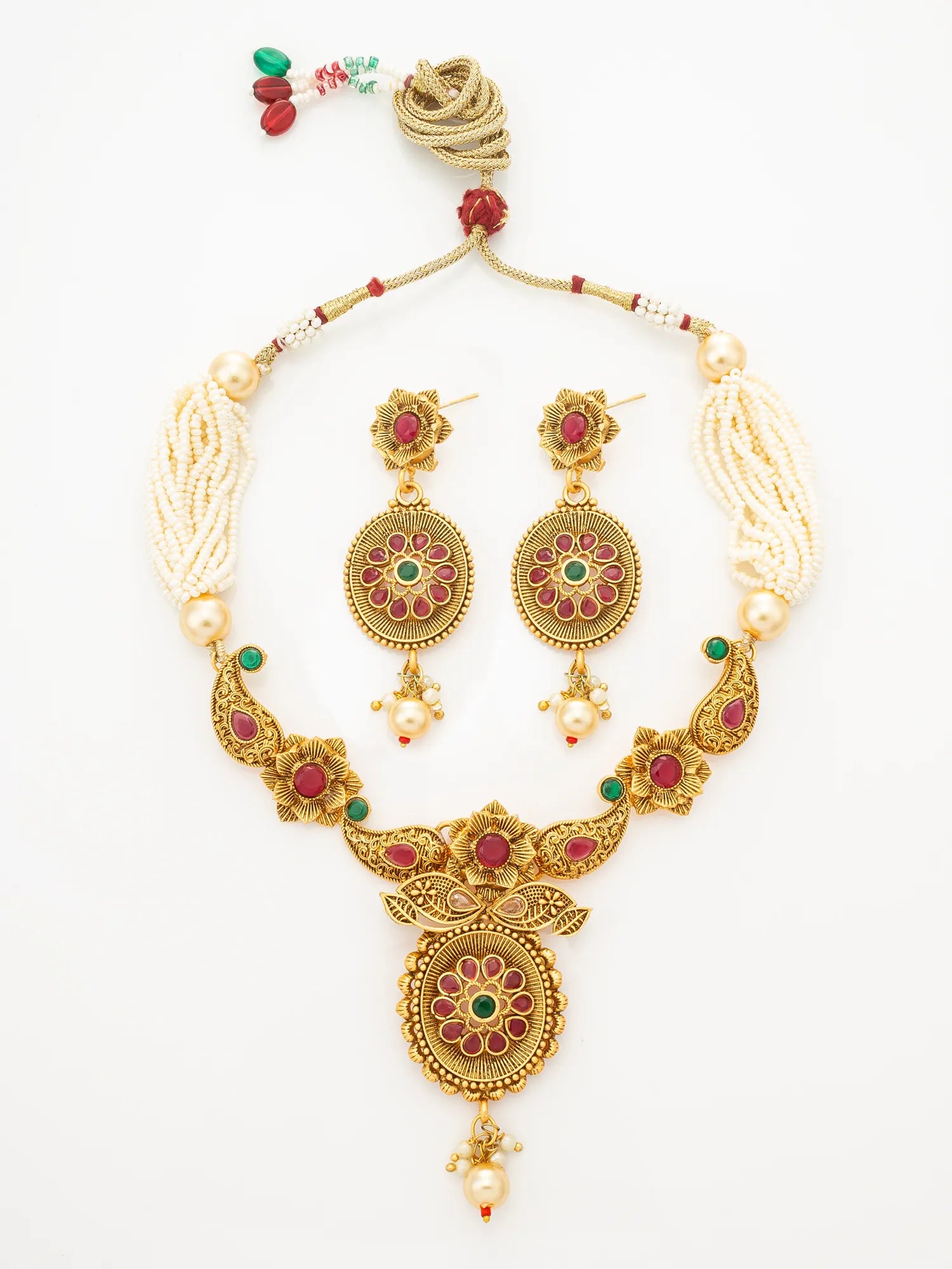 Gold-toned traditional necklace and matching drop earrings with cream pearl-like strands, red and green stone accents, and floral motifs, displayed on a plain white background.