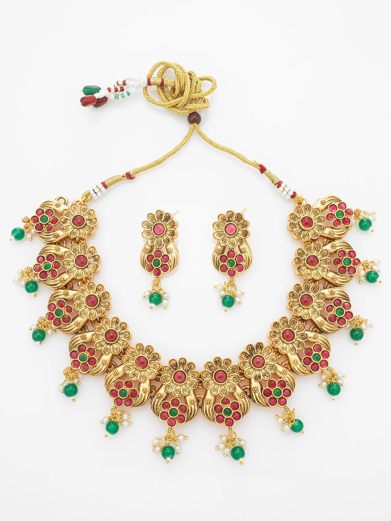 Gold-toned traditional necklace and matching earrings with red and green stone embellishments, displayed on a plain white background.