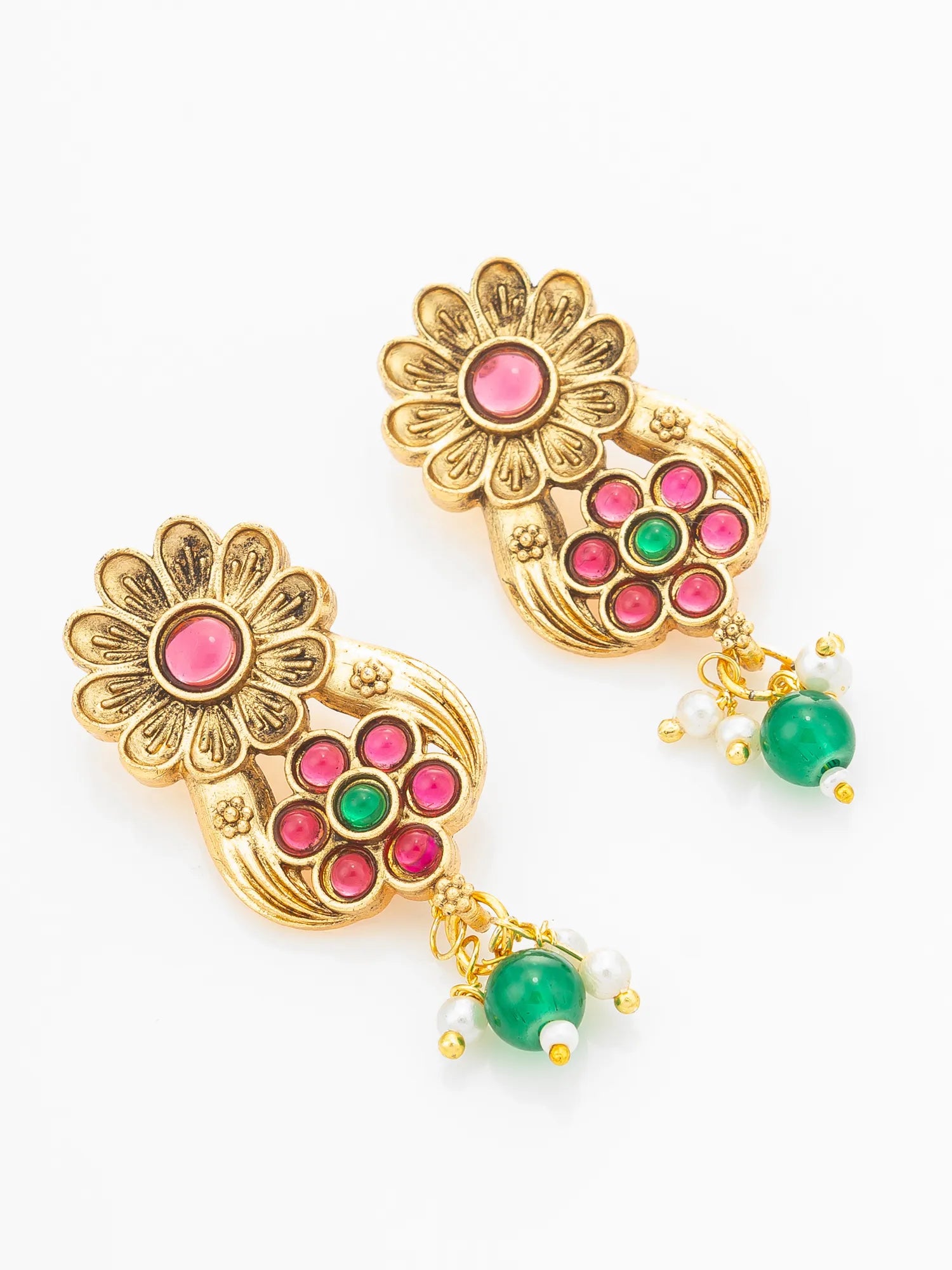 A pair of gold-toned Indian jhumka earrings decorated with pink and green stones, featuring a floral motif and dangling green bead charms with white pearl-like accents, set against a plain white background.
