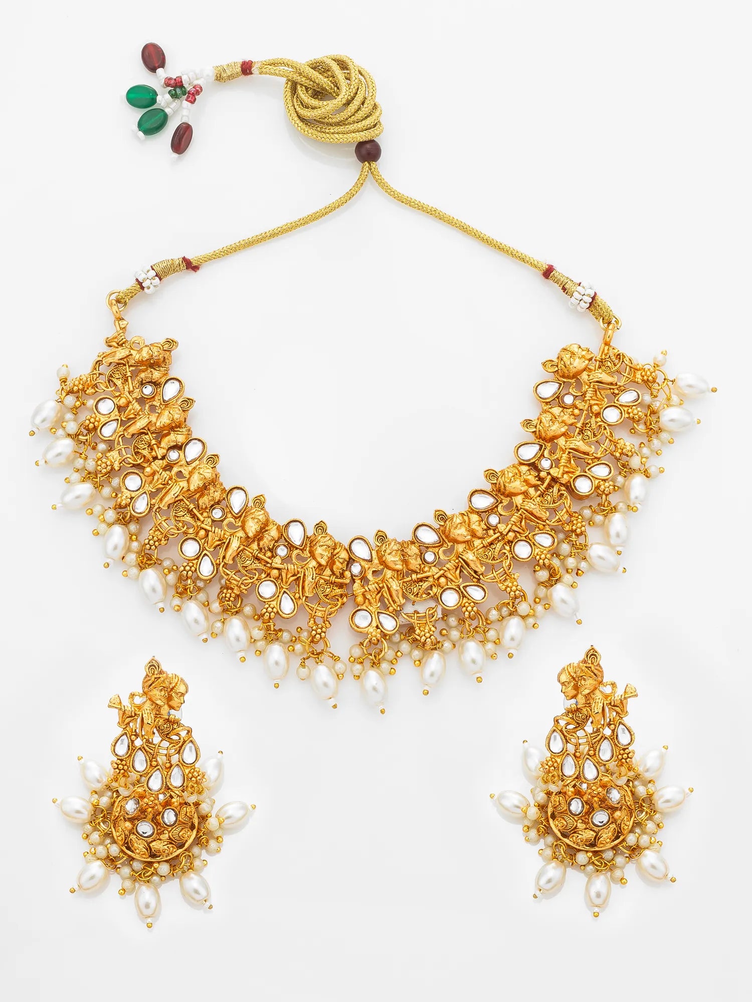 An ornate gold-toned traditional necklace set with matching drop earrings, decorated with white faux pearls and small red and green stone accents, displayed on a clean white background.