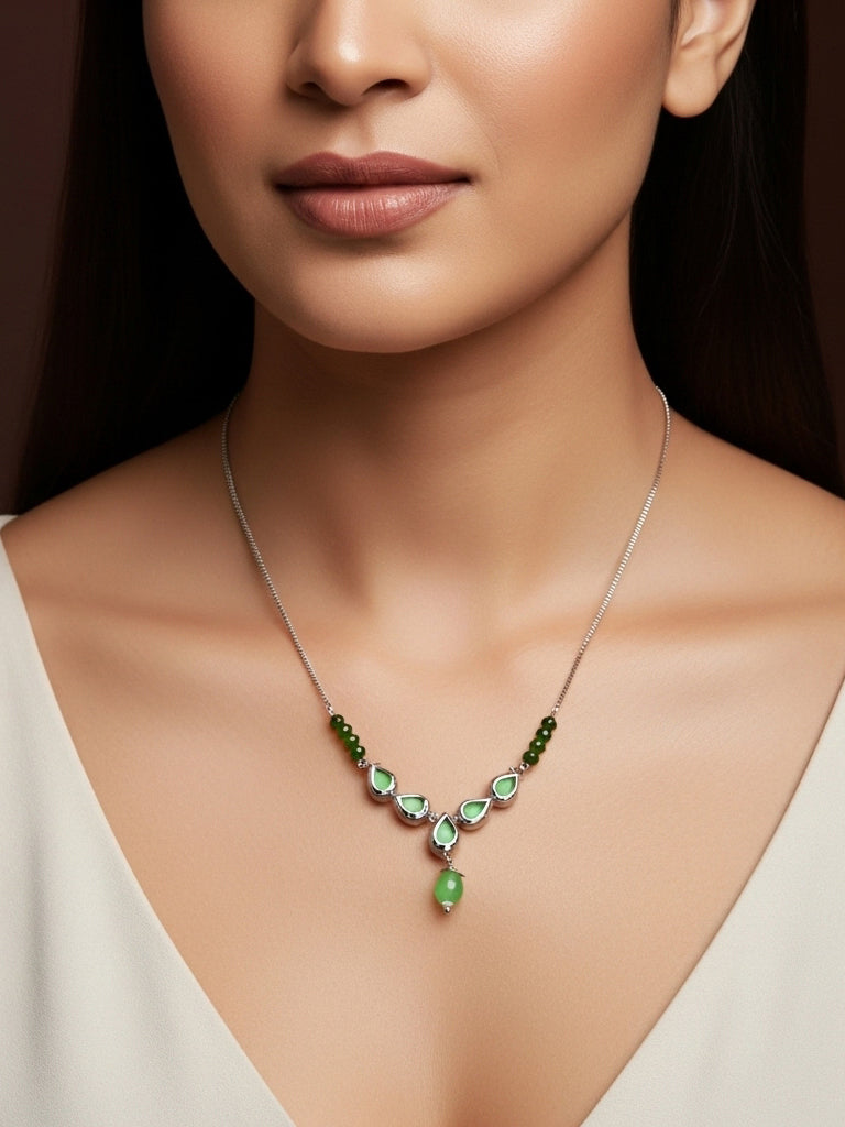 Close-up of a woman wearing a green gemstone necklace against a dark background