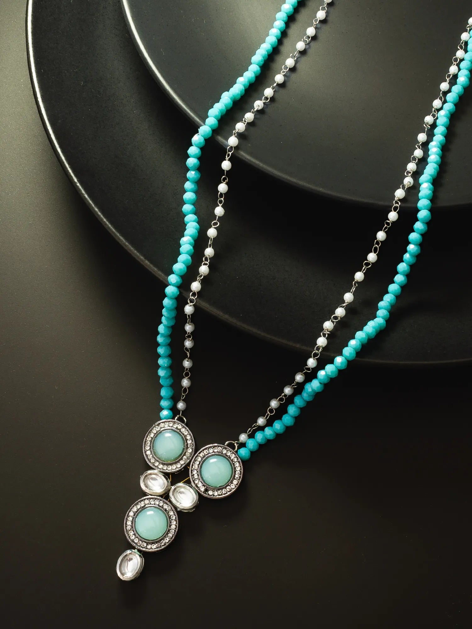 Turquoise beaded necklace with silver accents on a black background