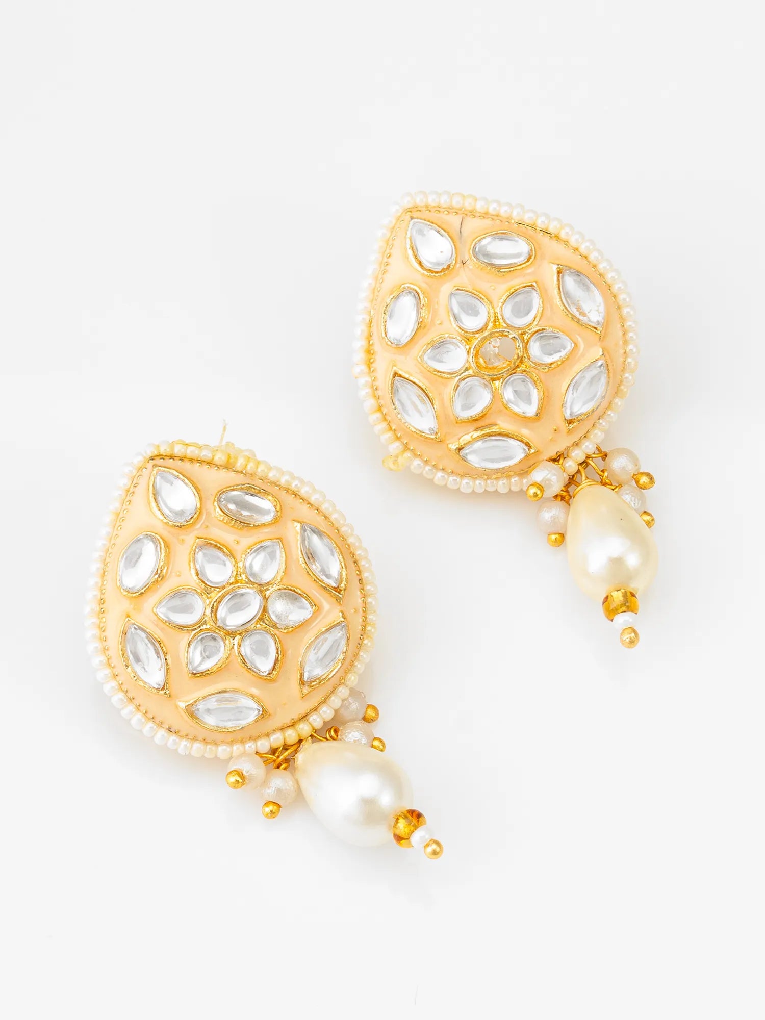 A pair of gold-toned teardrop-shaped earrings decorated with white stones in a floral pattern, bordered with small white pearls, and hanging from white pearl drops with gold accents, shown on a plain white background.