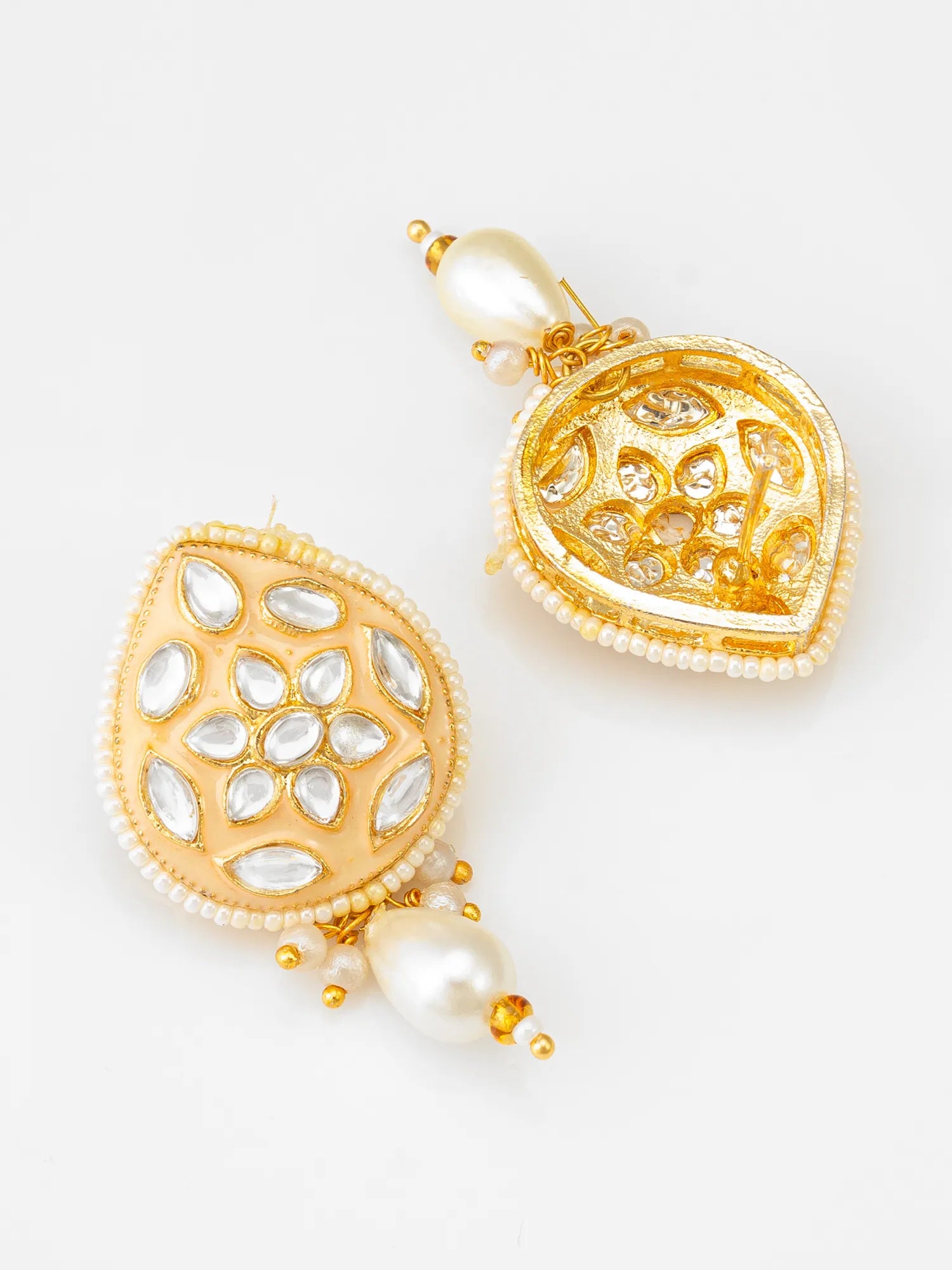 A pair of gold-toned Indian jhumka earrings decorated with white faux pearls and inlay stones, displayed on a clean white background.