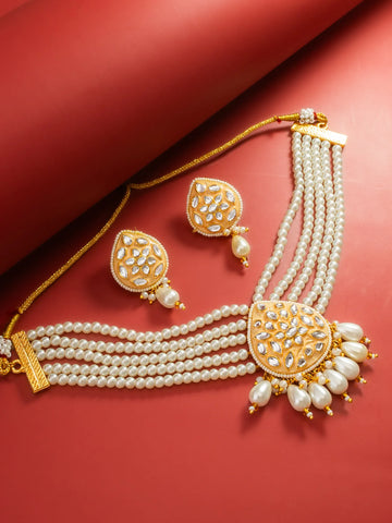 Gold-plated multi-strand pearl necklace and matching earrings with intricate stone embellishments, displayed on a textured red background.